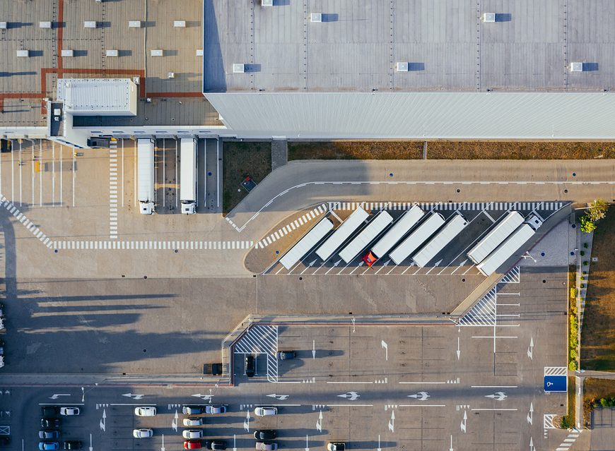 An overview of a production facility, with white trucks and cars parked outside