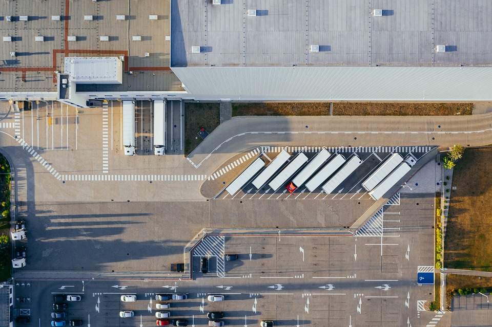 An overview of a production facility, with white trucks and cars parked outside